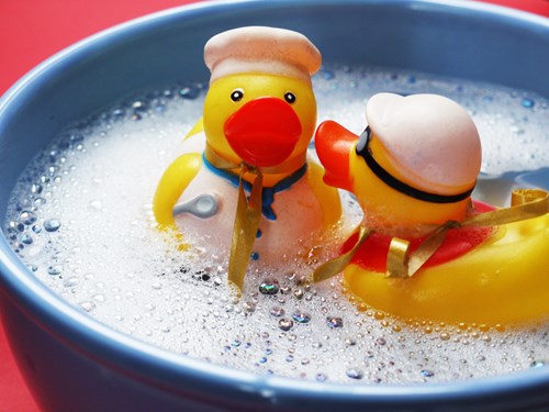 rubber duckies floating in a bucket of soapy water